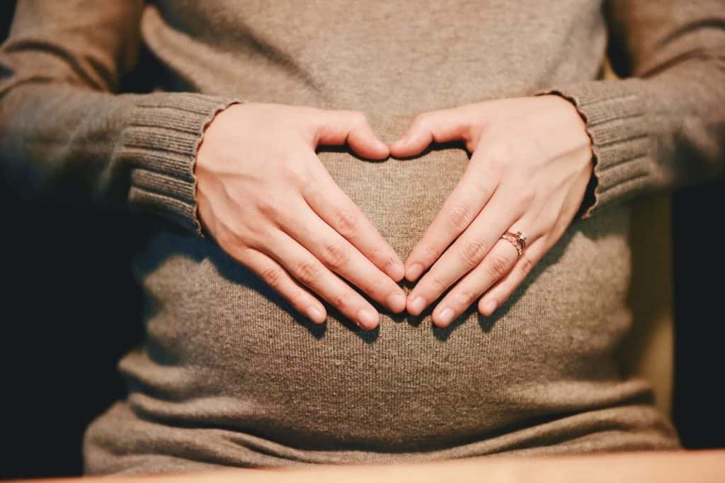pregnant woman forming a heart over her belly